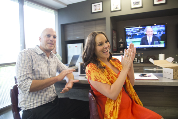 Chris Nelson and Kimberly Wacaser clap for coworker April Croswhite rings the office gong. 
