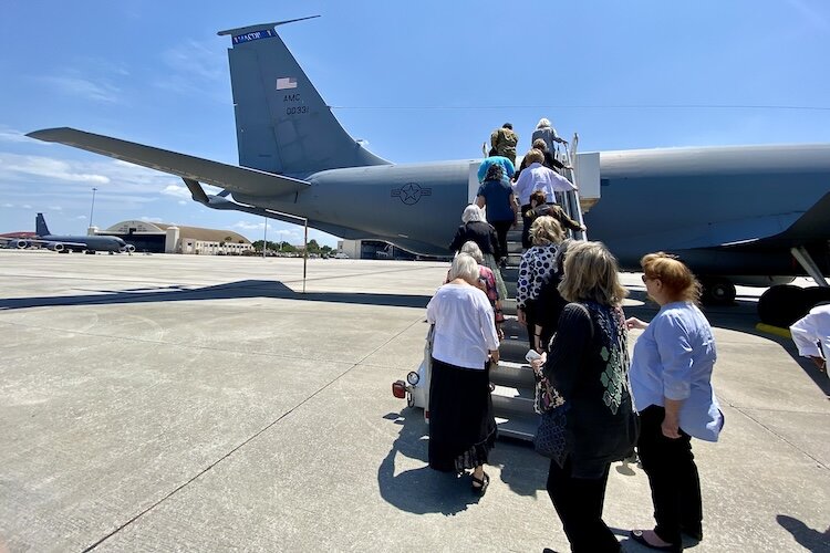 Athena Society of Tampa tour guests climb aboard as another KC-135 Stratotanker departs a nearby hangar. About 24 tankers are housed at MacDill.