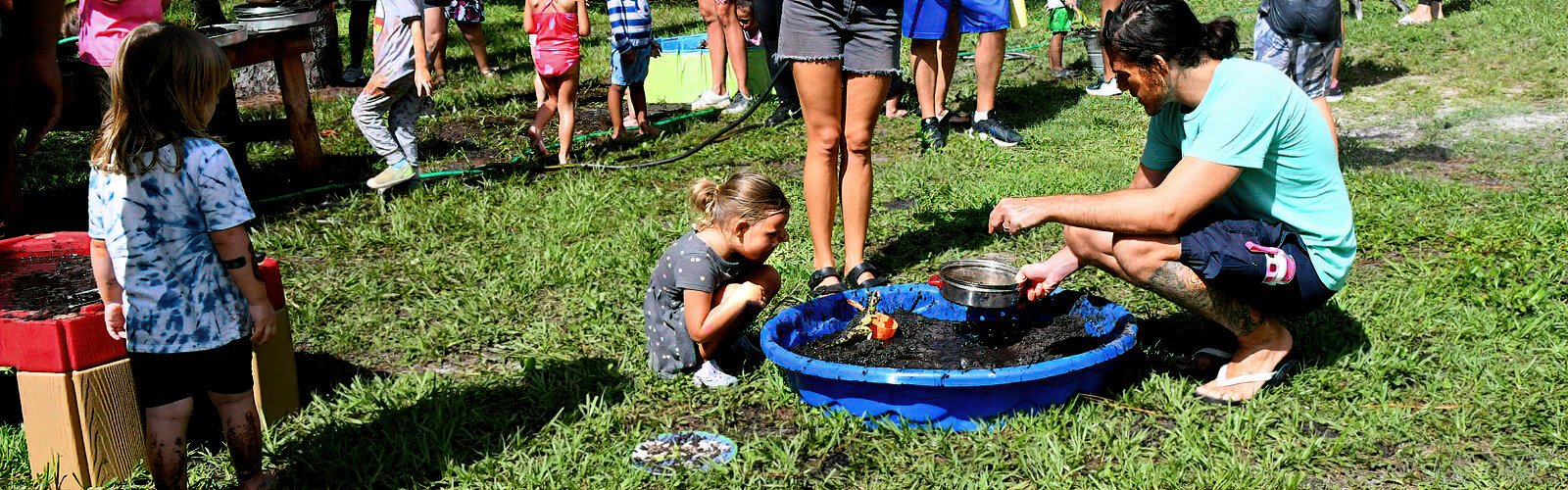 Dad Ron encourages daughter Autumn, 4, to play archaeologist and sift through the wet soil during Mud Day at Rowlett Park.