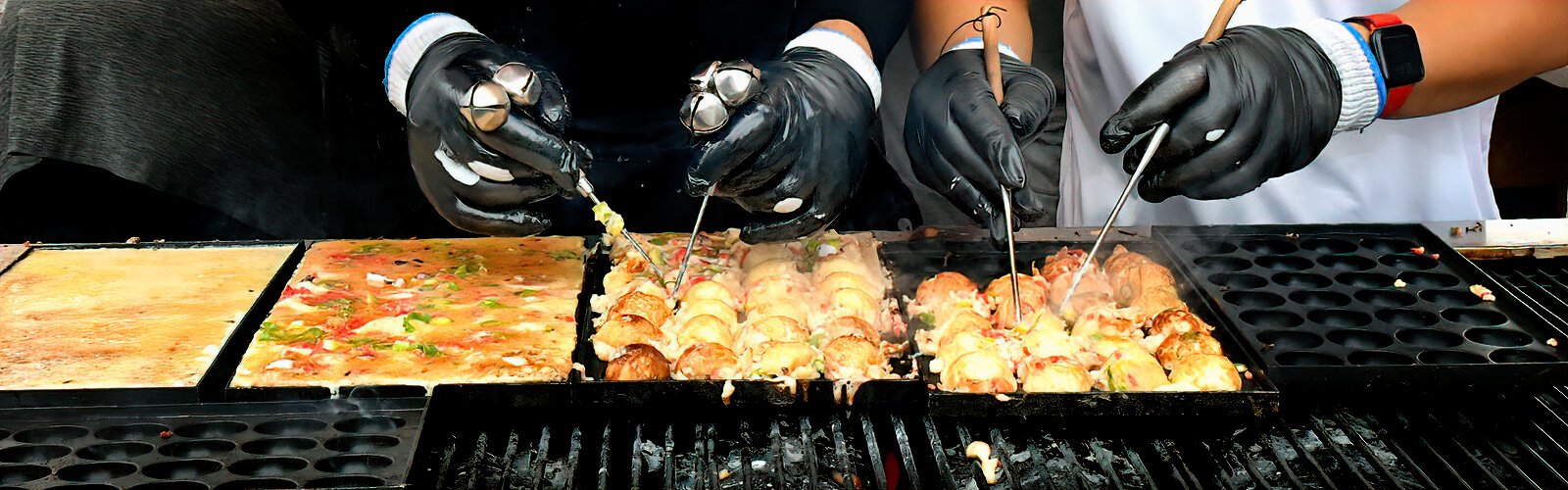 Takoyaki, ball-shaped Japanese snacks filled with diced octopus, are being prepared as orders come in.