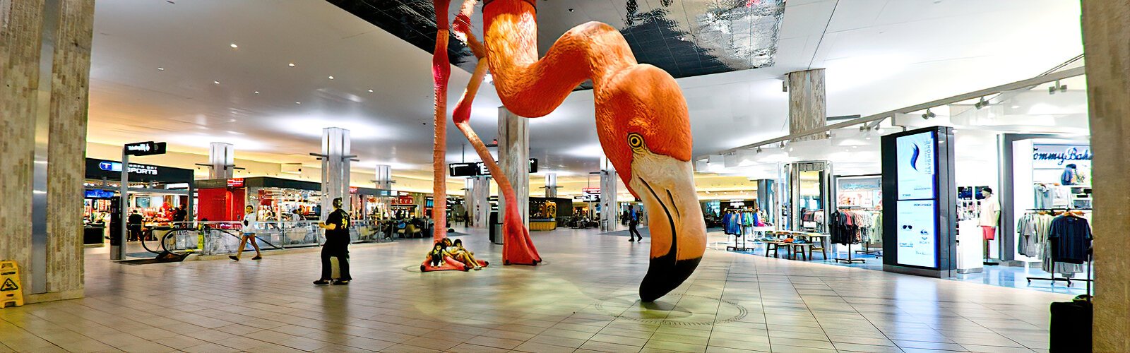 A traveling family finds a cozy spot in artist Matthew Mazzotta’s 22-foot-tall pink flamingo sculpture “Home” in Tampa International’s main terminal.