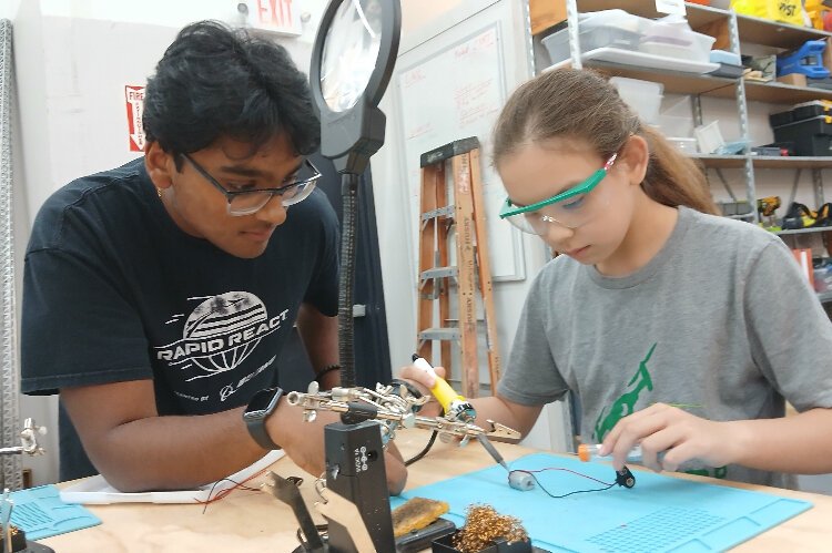 Two students solder a project during a summer camp at AMRoC Fab Lab.