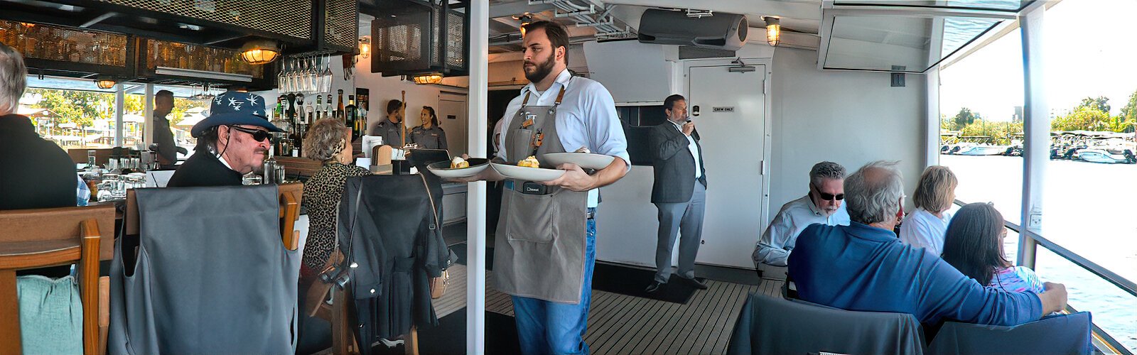 A server brings freshly-prepared dishes from a three-course lunch menu to guests at “the Bow and Stern Bar” as Rodney Kite-Powell shares insights on Tampa’s sights and history.