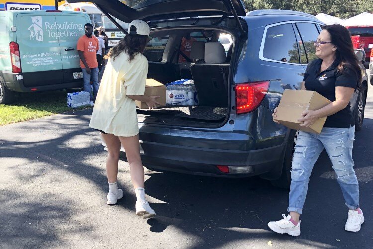 Volunteers load boxers of food into a vehicle during Rebuilding Together Tampa Bay's hurricane relief distribution event at the Children's Board of Hillsborough County's Ybor City offices.