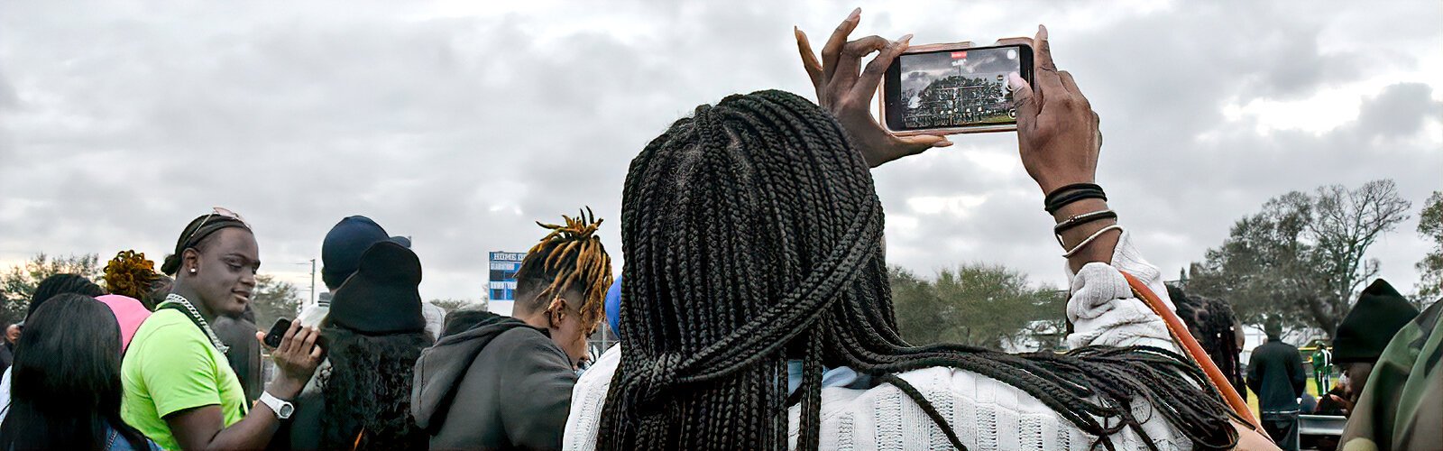 An audience member at the MLK Battle of the Bands uses a cell phone to capture Palm Beach's John F. Kennedy Middle School Mighty Marching Vikings performing.