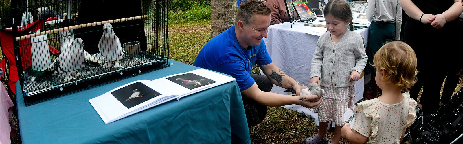 Pigeon foster Joe Sharp encourages Nora, 3, to pet a so-called “fancy pigeon”. These unusual pigeons were abandoned in a church, rescued by BHH and are now housed by Sharp.