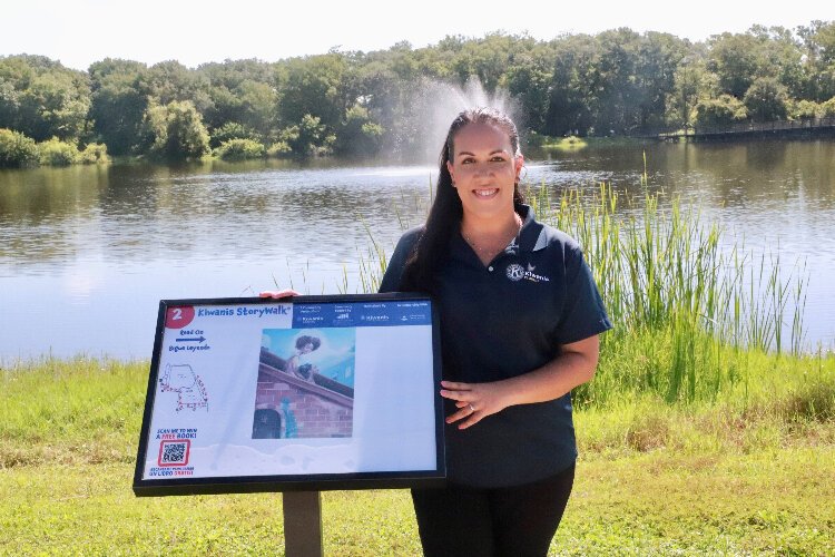 Amanda Malinowski, chair of the Kiwanis Club of Tampa StoryWalk program, with a story page at Carrollwood Village Park.